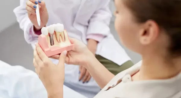 Closeup of unrecognizable female doctor pointing at tooth model while consulting patient, copy space